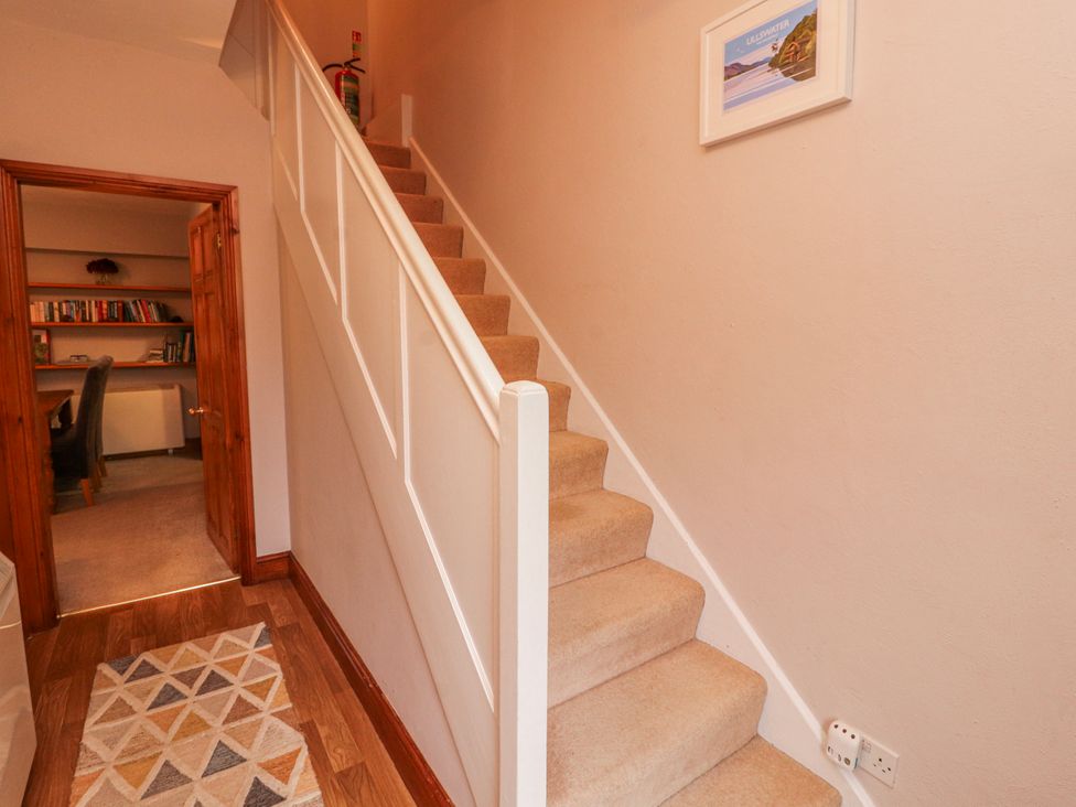 A hallway with a staircase and a door to another room at Greenbank Cottage Winster near Bowness-On-Windermere