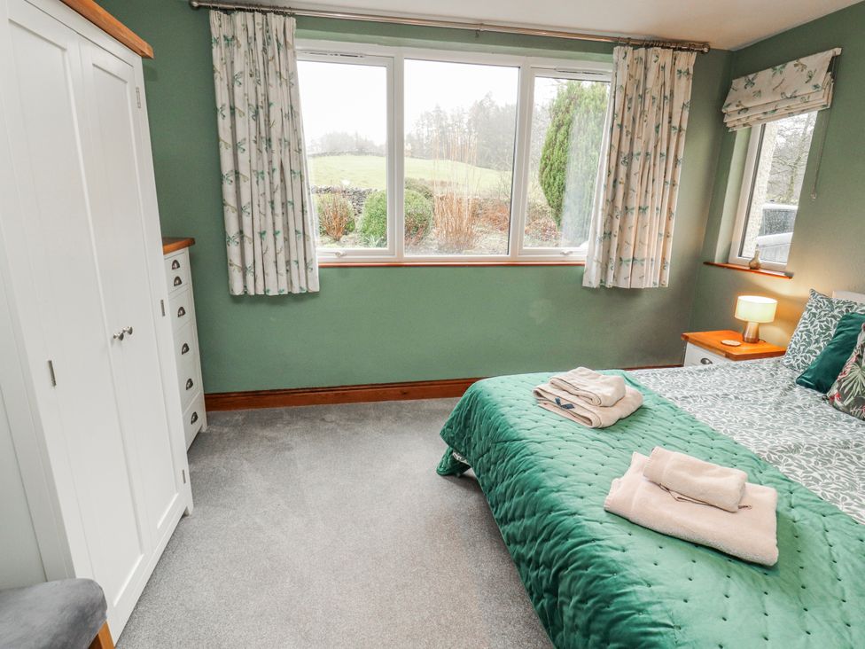 A bedroom with a bed and curtains at Greenbank Cottage in Winster near Bowness-On-Windermere