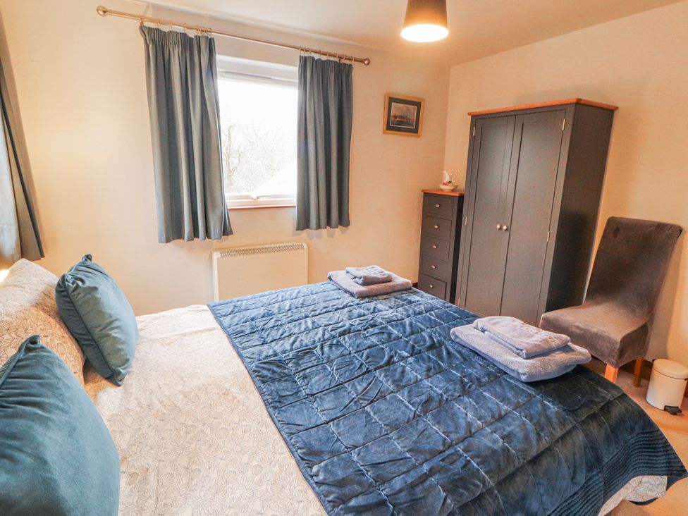 A bedroom with a bed and wardrobe at Greenbank Cottage in Winster near Bowness-On-Windermere