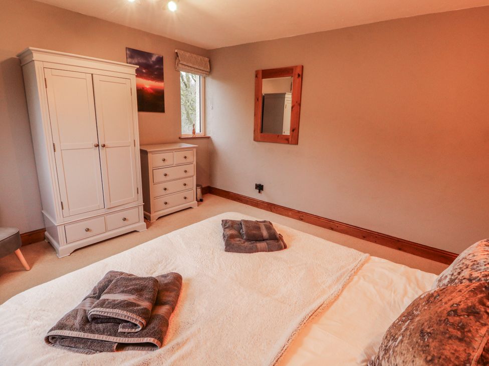 A bedroom with a bed and wardrobe at Greenbank Cottage in Winster near Bowness-On-Windermere