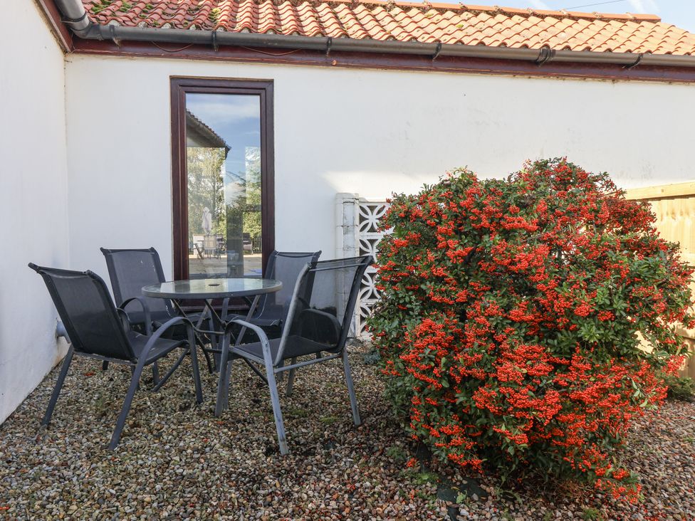 A garden with a table and chairs next to a bush at East Cottage in East Knapton near Rillington