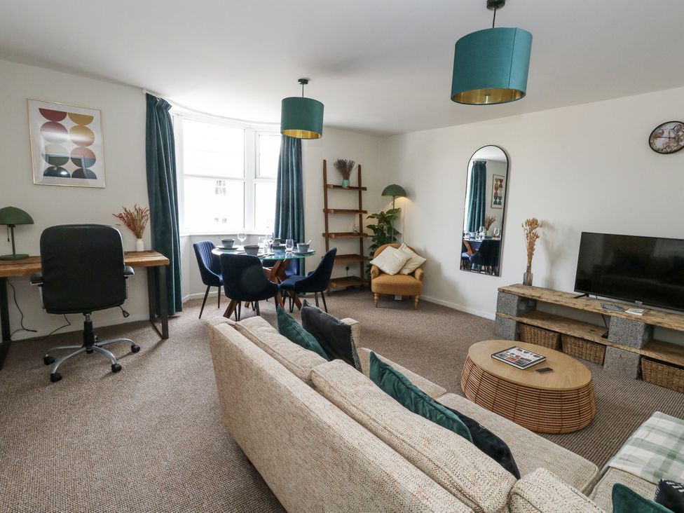 A living room with a sofa, coffee table, and dining area at Beachcomb in Weymouth
