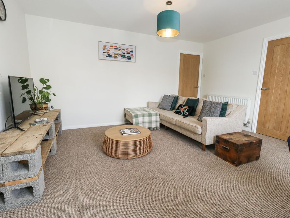 A living room with a sofa, coffee table, and television at Beachcomb in Weymouth