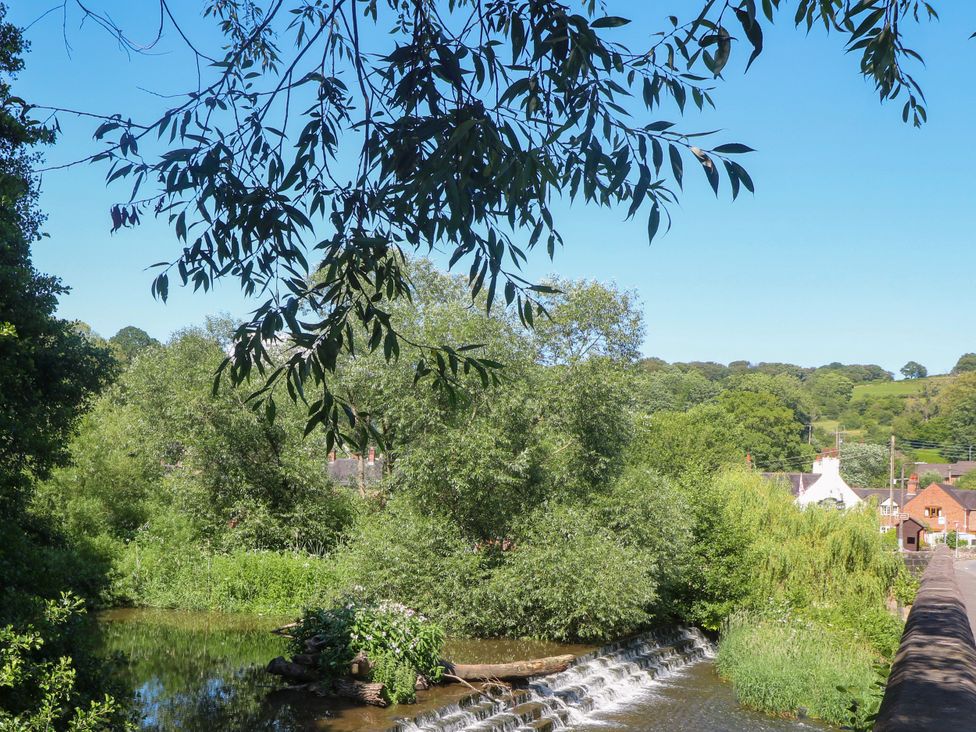 A view of a waterfall and trees with houses in the background at Bluebell Barn Stoke-on-Trent