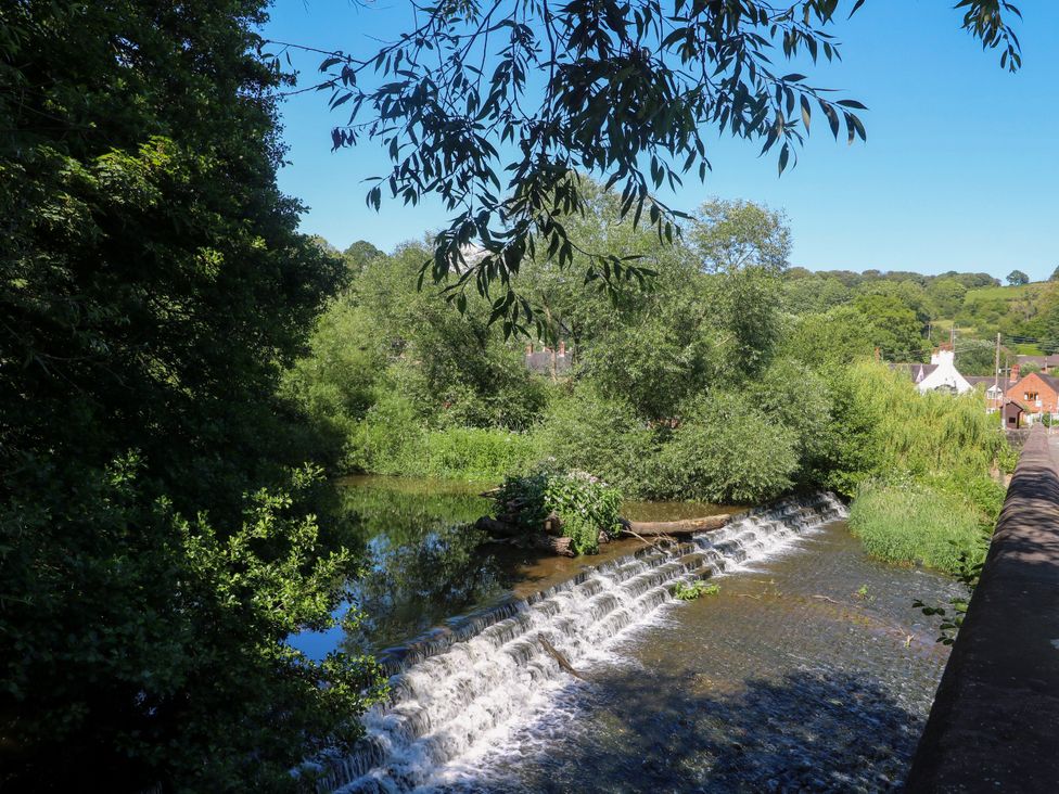 A river with a waterfall and trees at Bluebell Barn Stoke-on-Trent