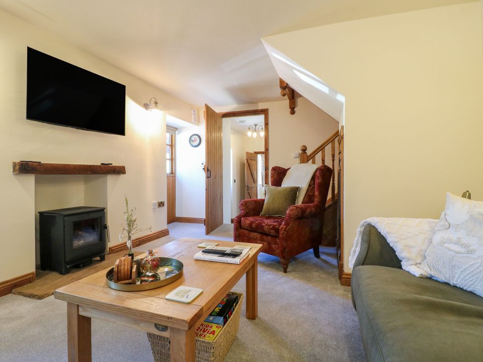 A living room with a fireplace and television at Bluebell Barn in Oakamoor