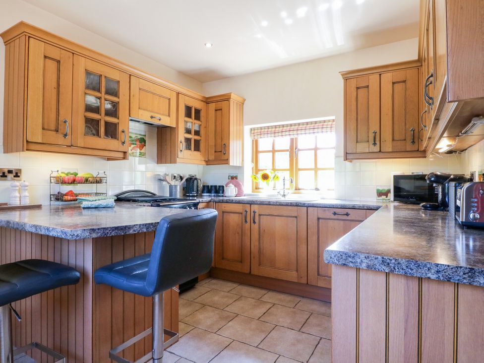 A kitchen with wooden cabinets and appliances at Bluebell Barn Oakamoor