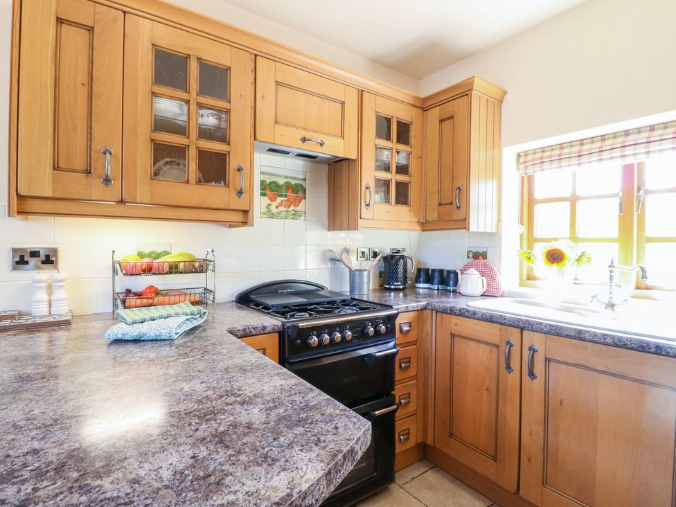 A kitchen with wooden cabinets and an oven at Bluebell Barn in Oakamoor