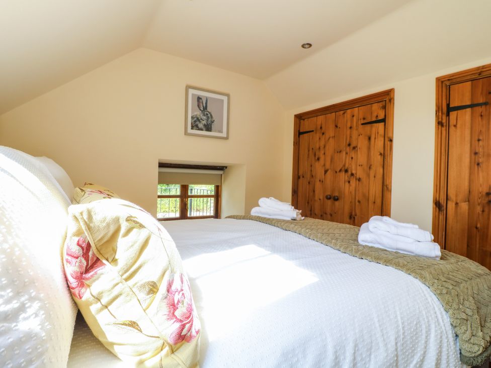 A bedroom with a bed and artwork at Bluebell Barn Oakamoore