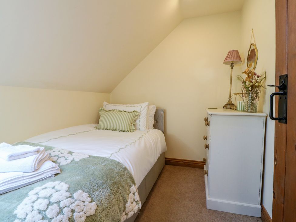 A bedroom with a single bed and bedside lamp at Bluebell Barn in Oakamoor