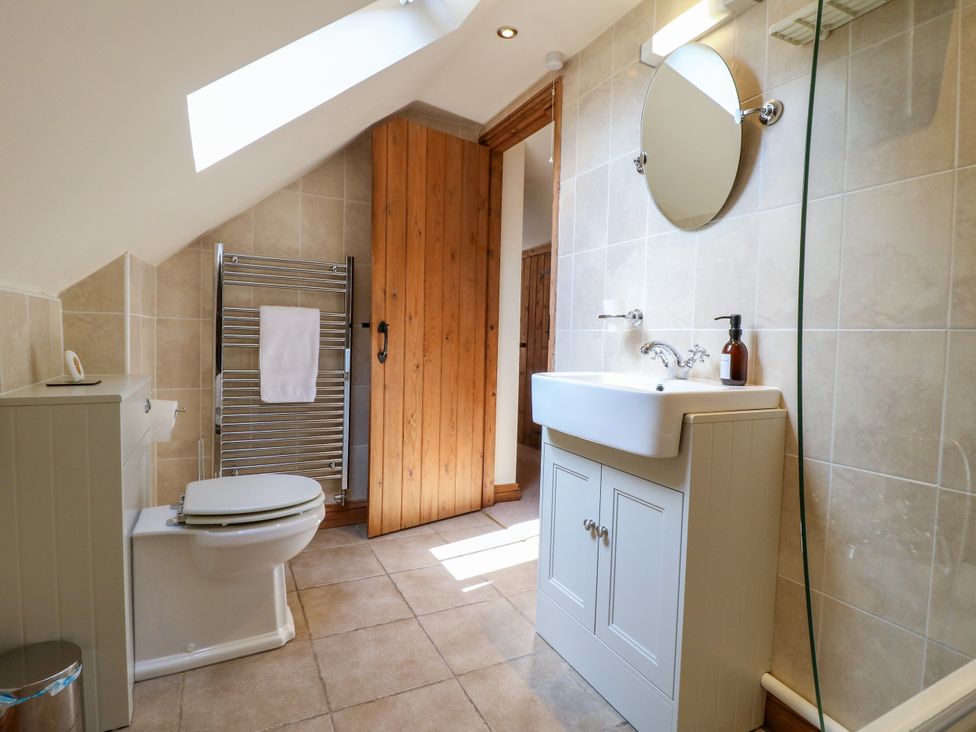 A bathroom with a toilet, sink, and towel rack at Bluebell Barn in Oakamoor