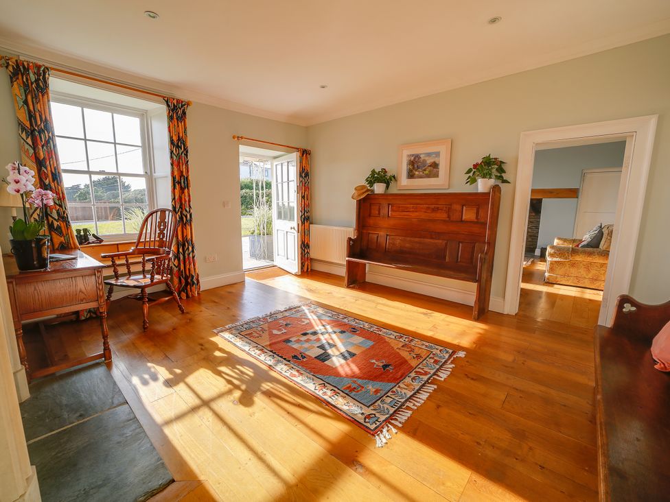 A living room with a bench and a desk at Porthcothan House in St Merryn