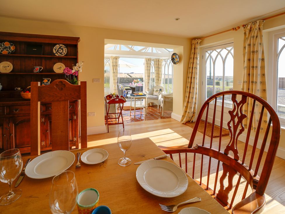 A dining room with a table set for meals at Porthcothan House in St Merryn