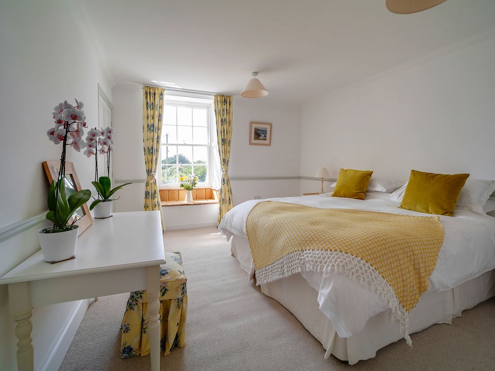 A bedroom with a bed and window at Porthcothan House in St Merryn