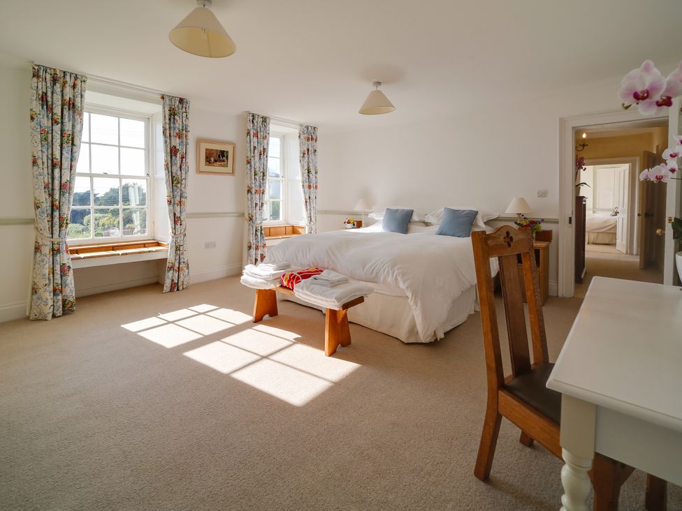 A bedroom with a bed and windows at Porthcothan House St Merryn