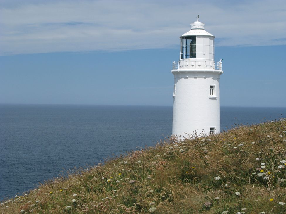 A lighthouse overlooking the sea at Porthcothan House in Porthcothan
