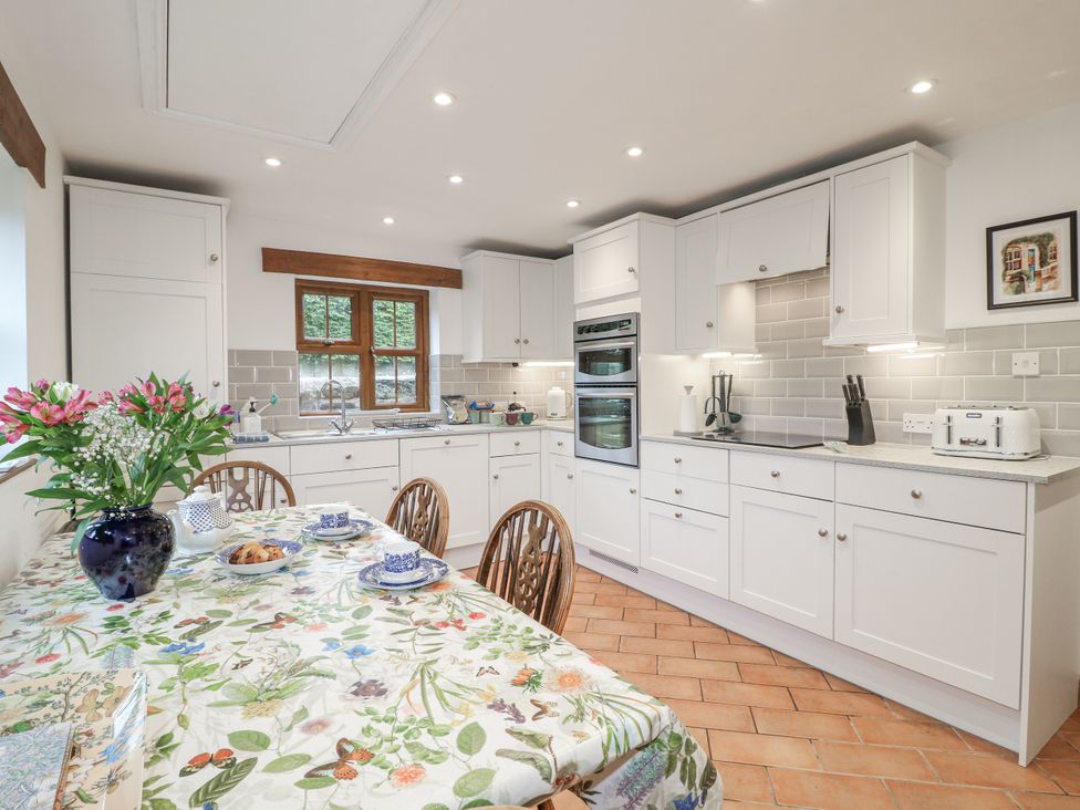 A kitchen with cabinets and a dining table at Yoxall Cottage in Stoke-on-Trent