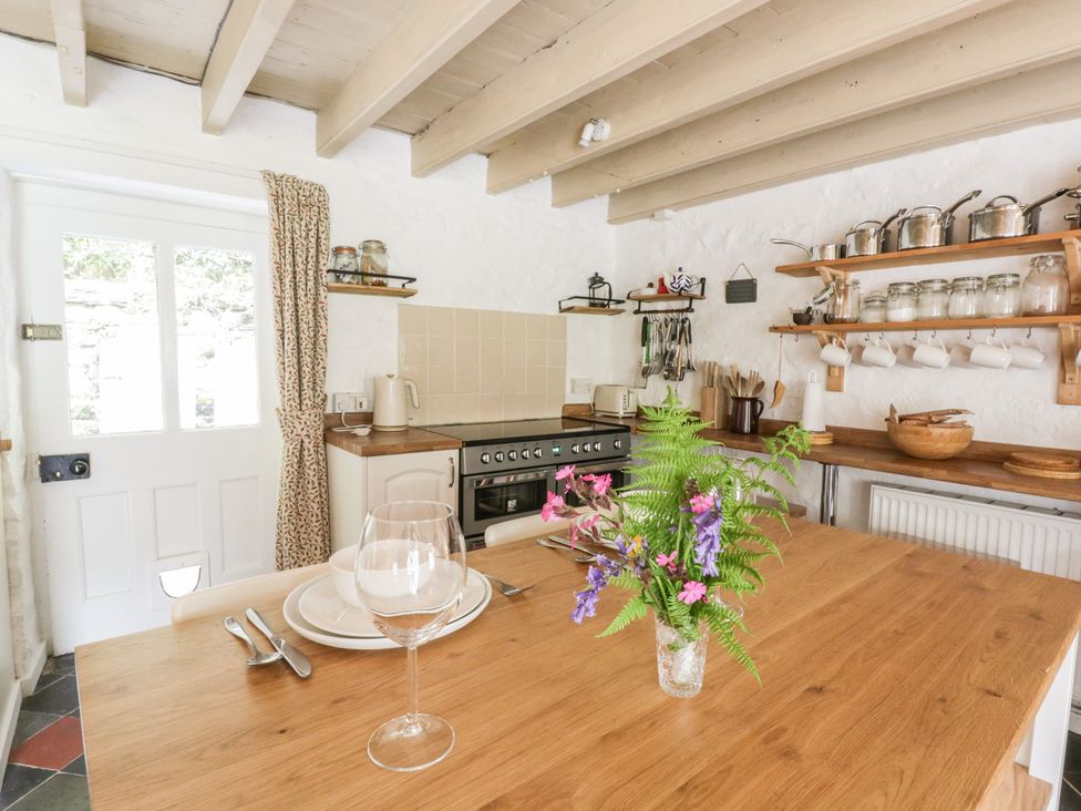 A kitchen with a wooden table and utensils on a shelf at Sycamore Vestry in Pontfaen near Fishguard