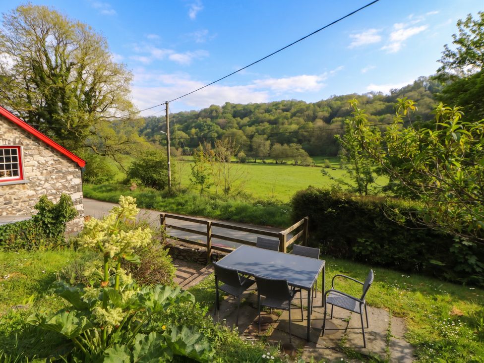 An outdoor seating area with a table and chairs at Sycamore Vestry Pontfaen near Fishguard