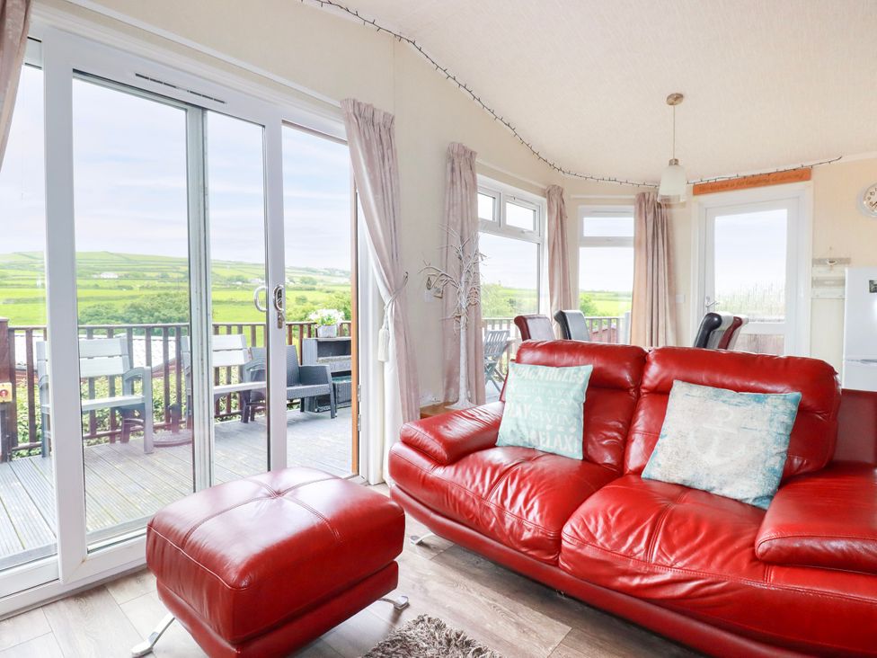 A living room with a red sofa and sliding doors at Chi Prenn Byhan in Tintagel