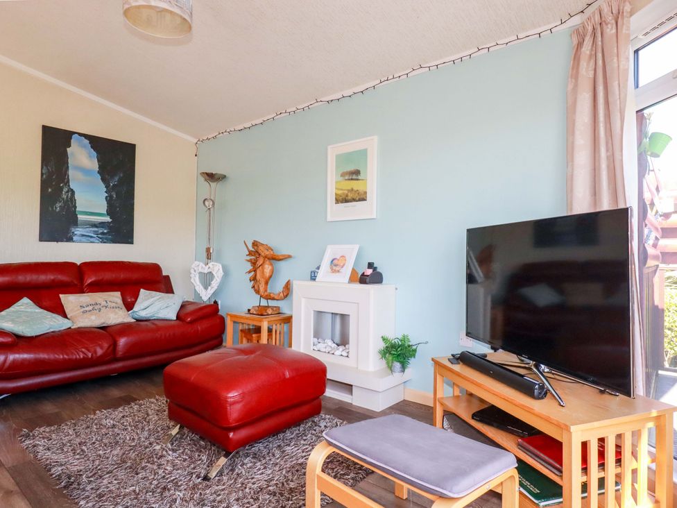 A living room with a red couch and television at Chi Prenn Byhan in Tintagel