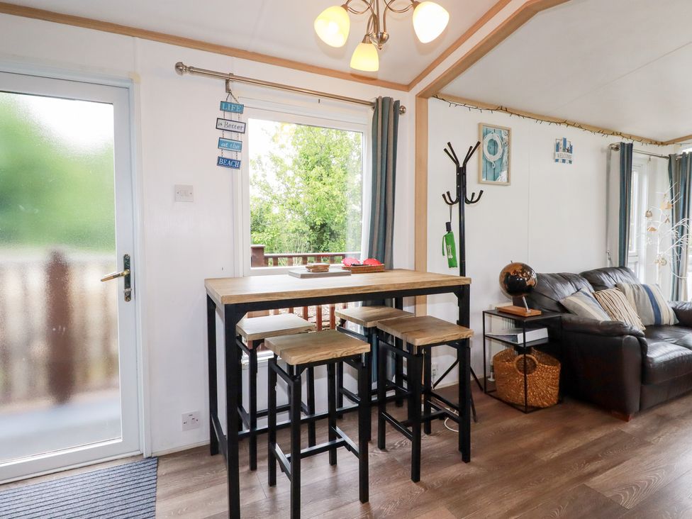 A dining area with a bar table and stools at Orchard View in Bossiney near Tintagel