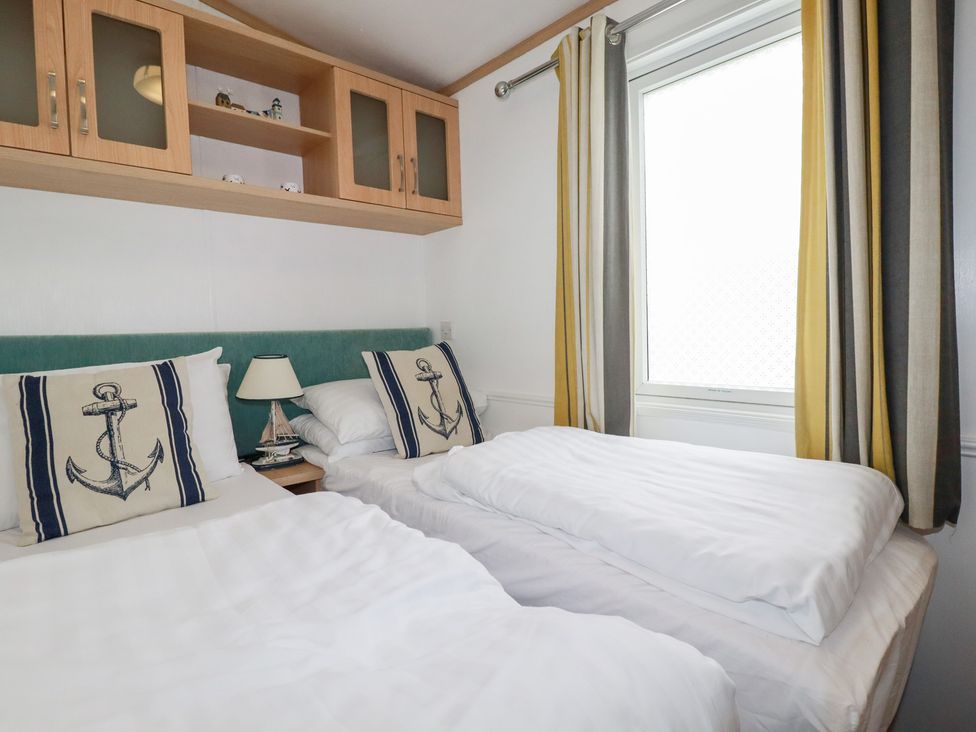 A bedroom with two beds and a window at Orchard View in Bossiney near Tintagel