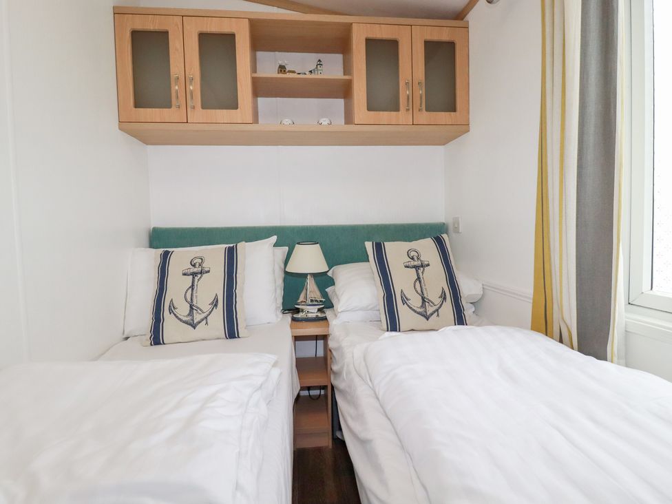 A bedroom with two beds and a lamp on a side table at Orchard View in Bossiney near Tintagel
