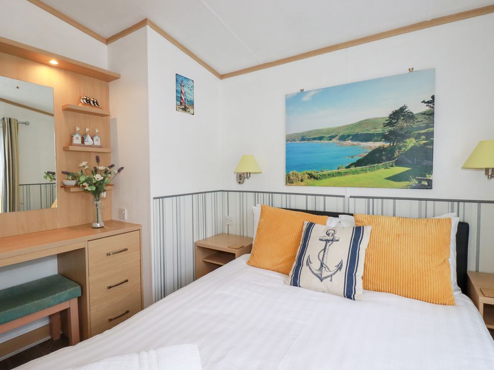 A bedroom with a bed and mirror at Orchard View in Bossiney near Tintagel