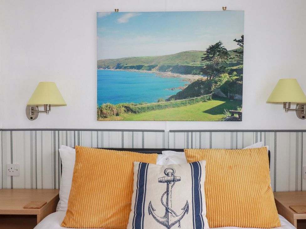 A bedroom with pillows and wall art at Orchard View in Bossiney near Tintagel