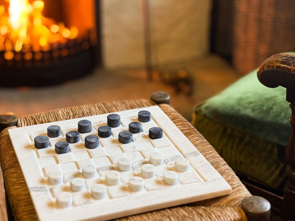 A checkerboard with black and white pieces next to a fireplace at The Captain's Nest in Bunbeg, County Donegal