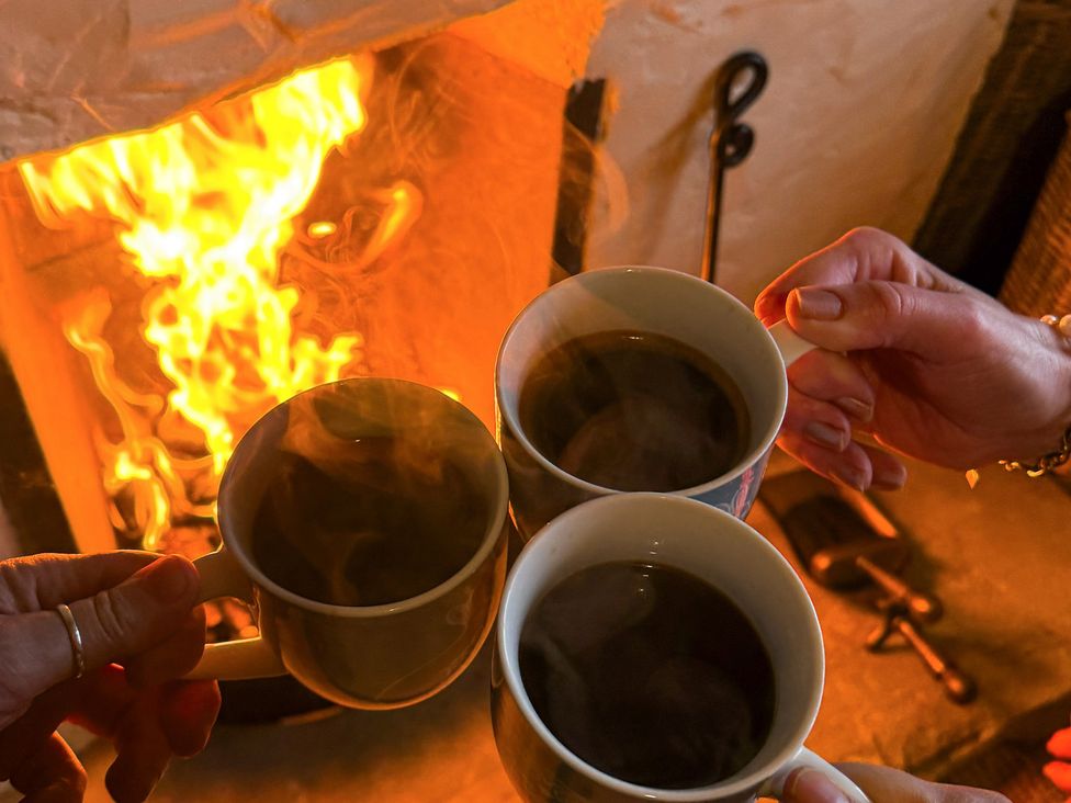 Three cups held in front of a fireplace at The Captain's Nest in Bunbeg, County Donegal