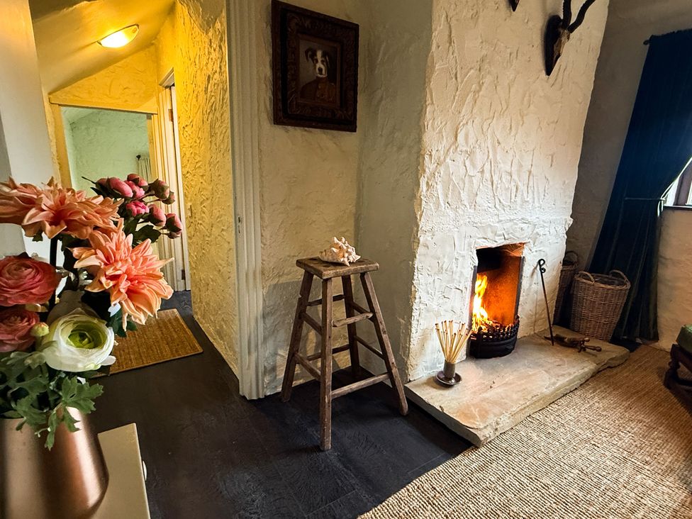 A living room with a fireplace and flowers at The Captain's Nest in Bunbeg, County Donegal