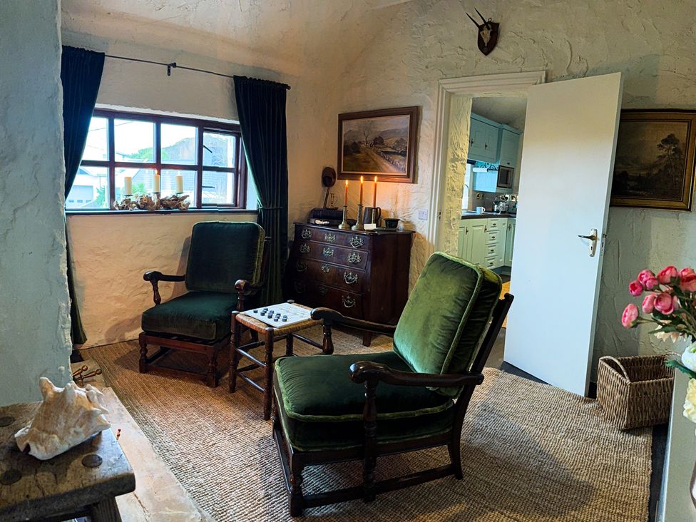 A living room with green armchairs and a table at The Captain's Nest in Bunbeg, County Donegal