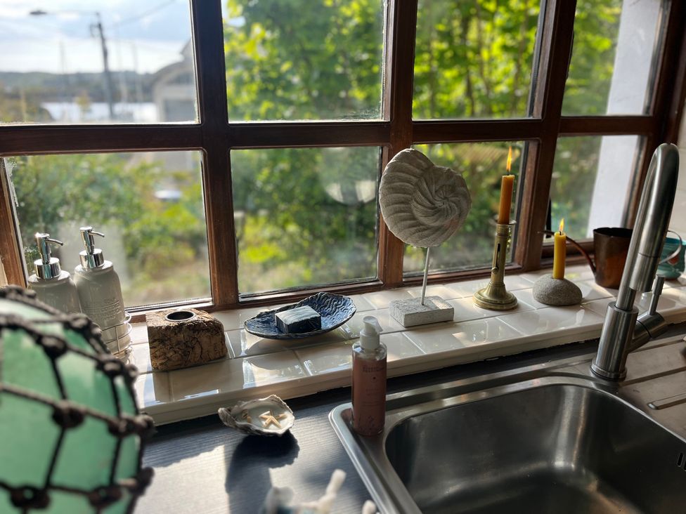 A kitchen window with various items including soap bottles and candles at The Captain's Nest in Bunbeg, County Donegal