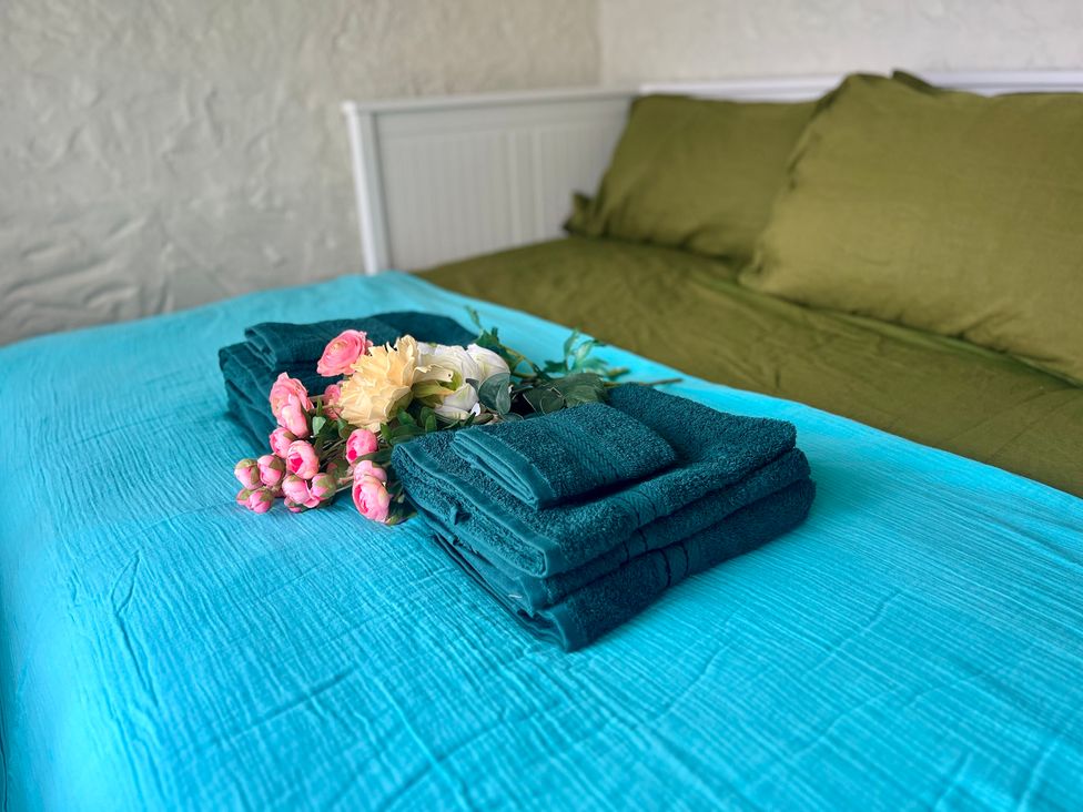 A bed with towels and flowers arranged on top at The Captain's Nest in Bunbeg, County Donegal