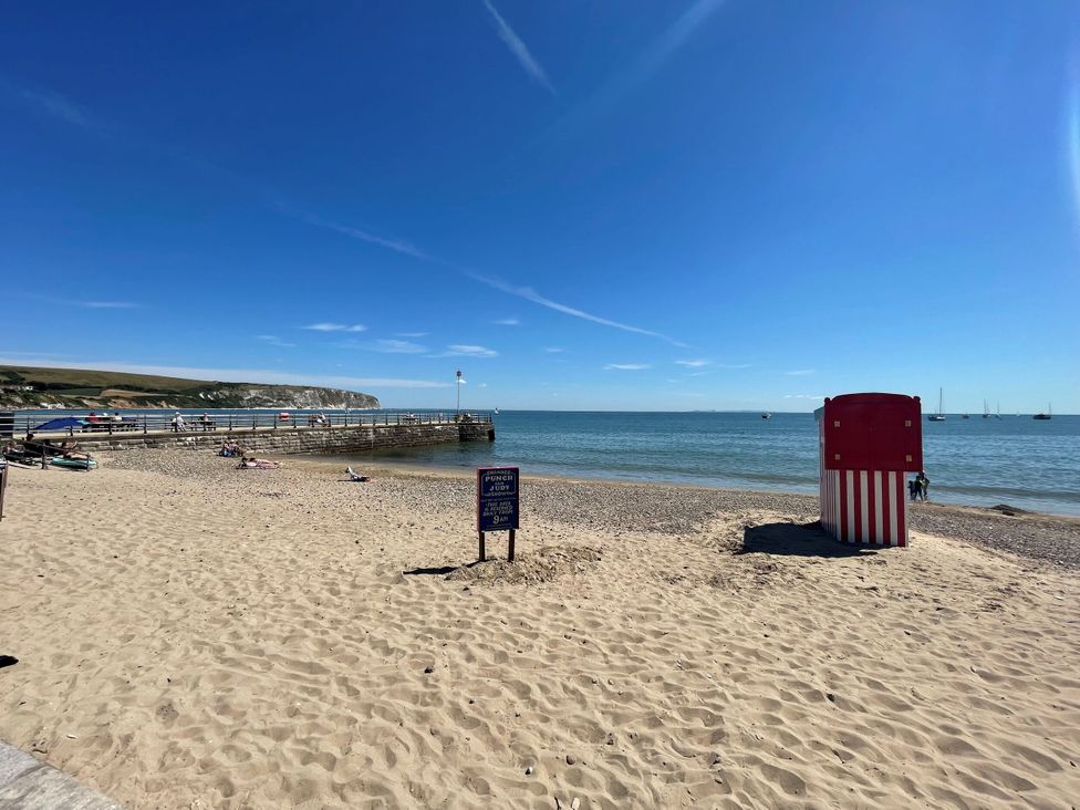 A beach with a pier and a beach hut at The Barn in Lytchett Matravers