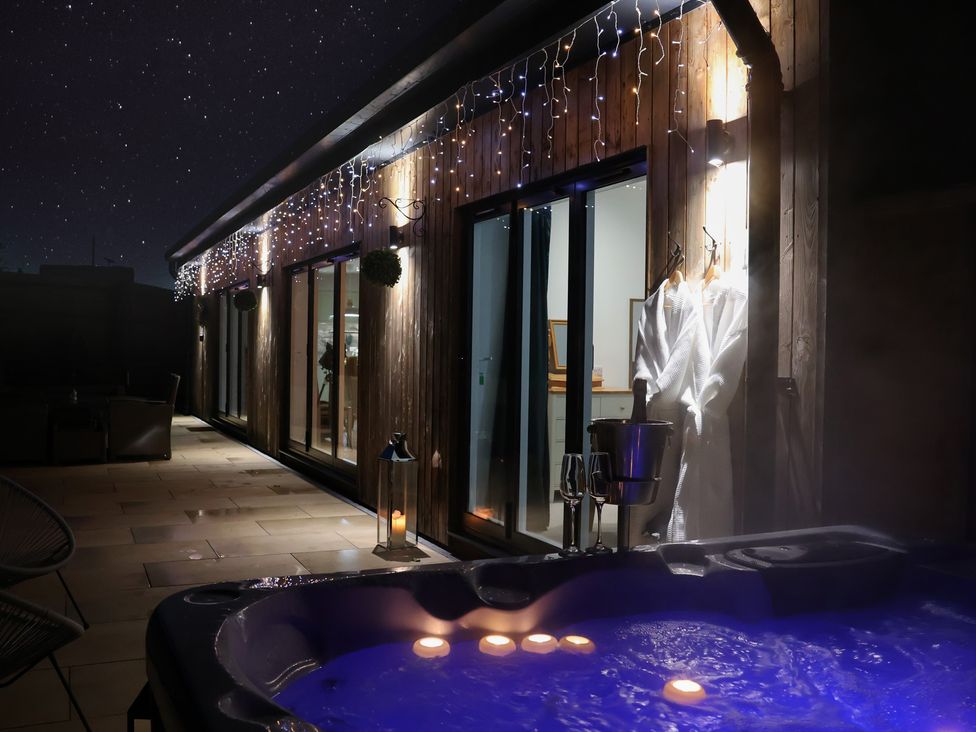 An outdoor area with a hot tub and seating at The Barn in Lytchett Matravers