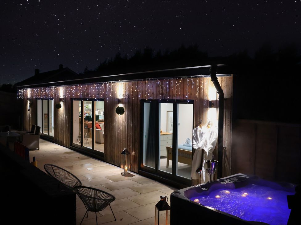 An outdoor area with a hot tub and wooden exterior at The Barn in Lytchett Matravers