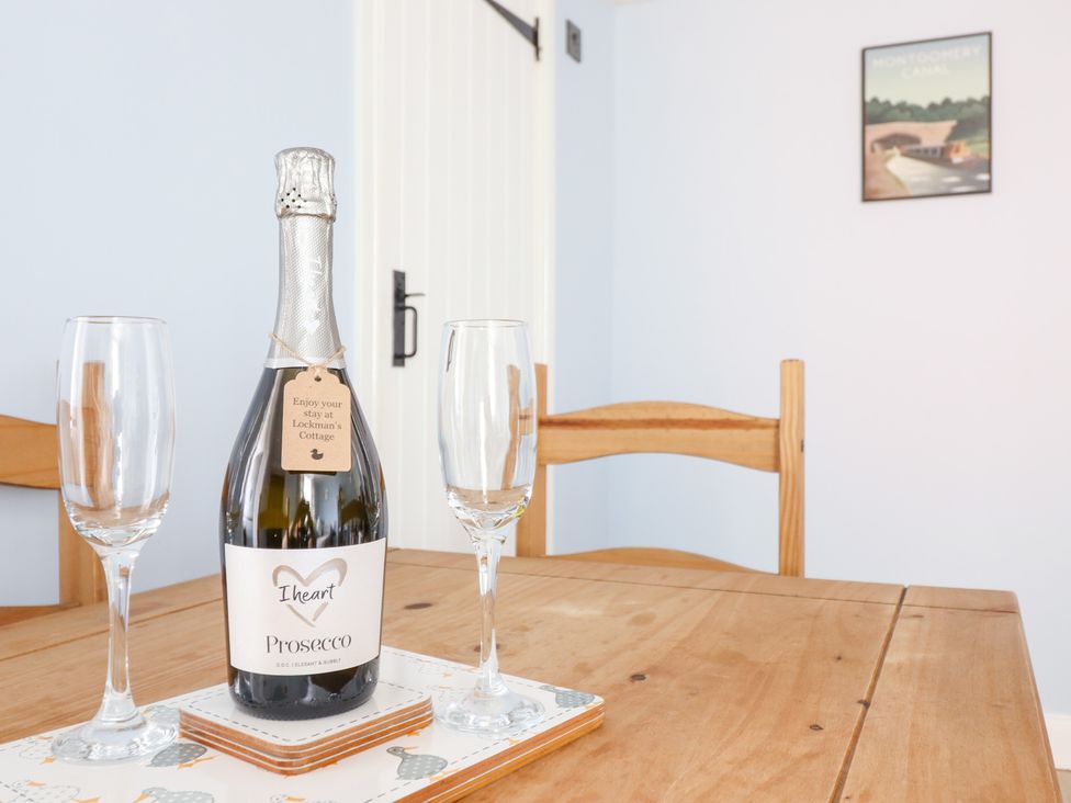 A bottle of prosecco with glasses on a table at Burgedin Locks Cottage Arddleen near Llandrinio