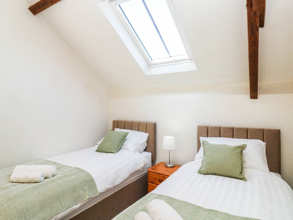 A bedroom with two beds and a skylight at 3 Town Farm Court in Newton Abbot