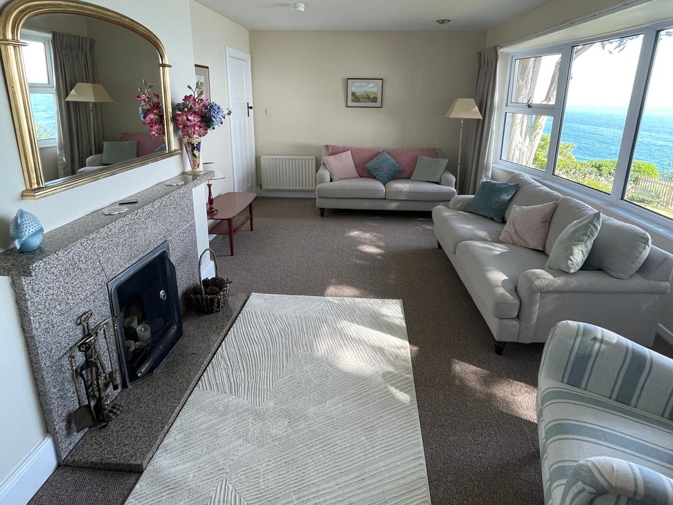 A living room with two sofas a fireplace a large mirror and a window with a sea view at Rocklea Seaside Cottage in Newcastle County Down