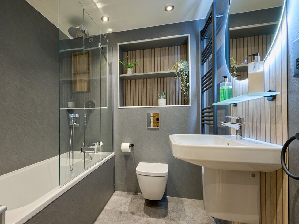A bathroom with a bath tub, toilet, sink, and shower at Riverside Park 1 in Keswick