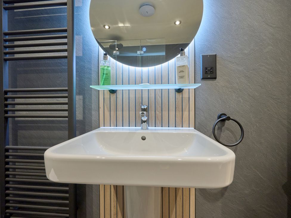 A wash basin with a mirror and shelf at Riverside Park 1 in Keswick