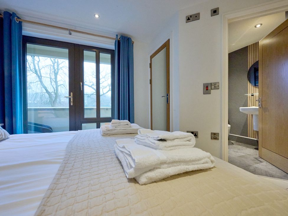 A bedroom with two doors and towels on the bed at Riverside Park 1 in Keswick