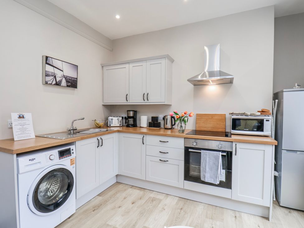 A kitchen with sink, washing machine, and appliances at 24 Baxtergate in Whitby