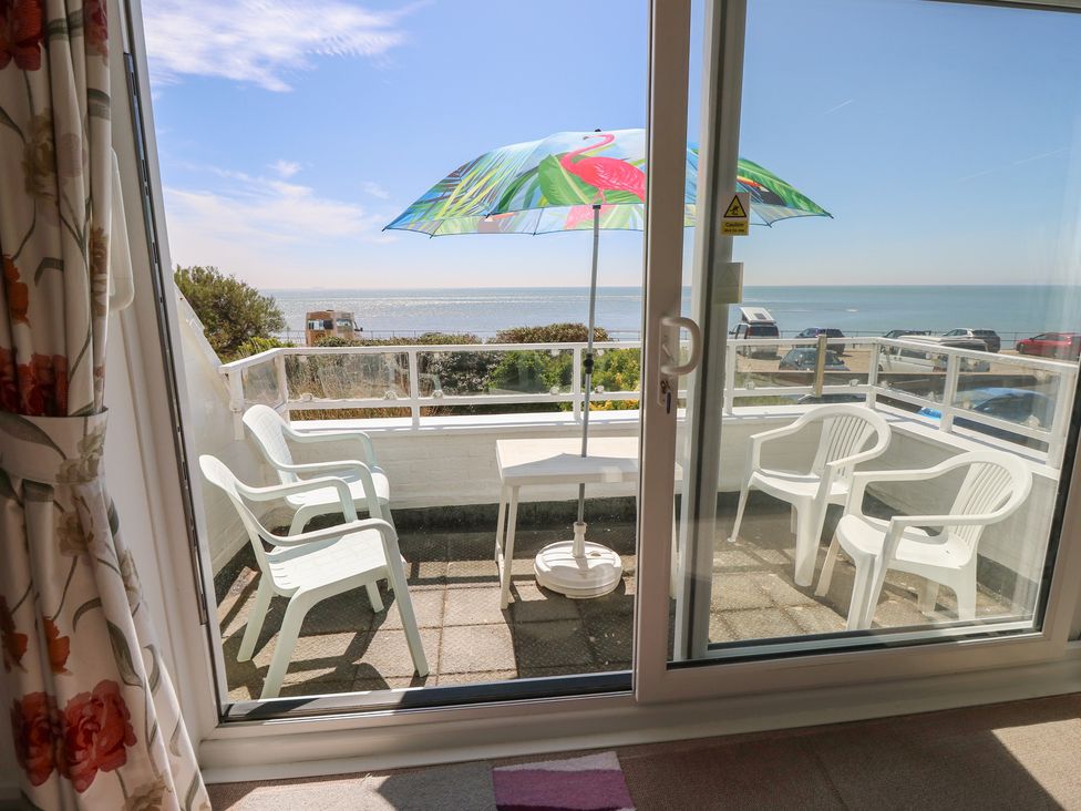 A balcony with chairs and a table overlooking the sea at Bella vista in Selsey, West Sussex