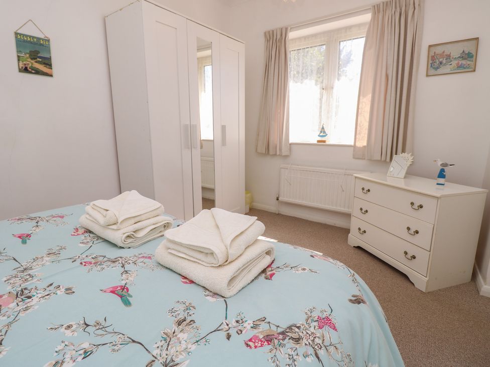 A bedroom with towels on the bed and a wardrobe at Bella Vista Selsey, West Sussex