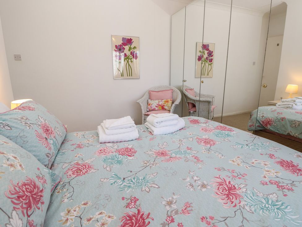 A bedroom with a bed, chair, and towels at Bella vista in Selsey, West Sussex