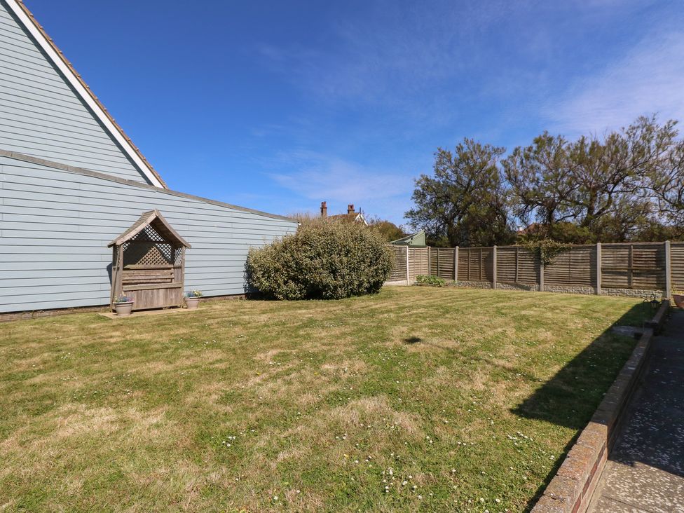 A garden with grass and a bench at Bella Vista in Selsey, West Sussex